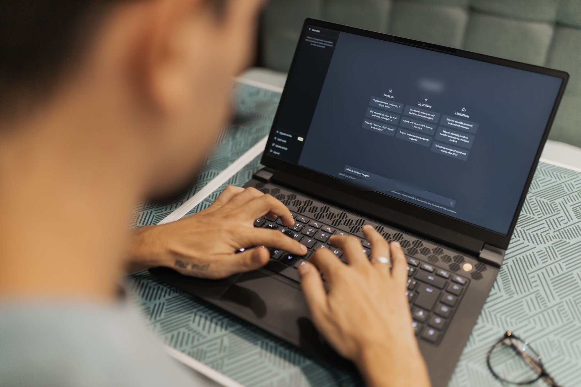 Someone typing to an AI assistant on a laptop. Illustrative photograph.